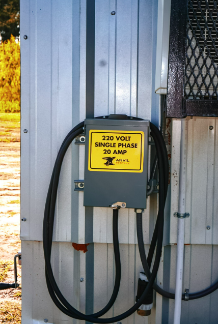 Exterior electrical connection box on an Anvil Rentals unit labeled 220 volt single phase 20 amp