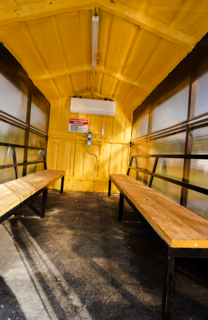 Insulated interior of an Anvil Rentals unit with bench seating and a wall-mounted air conditioning head