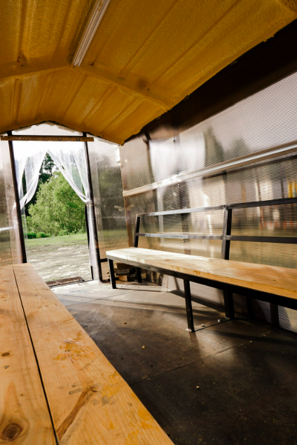 Daylight interior of an Anvil Rentals trailer with wooden bench seating along both walls and the entry curtain open